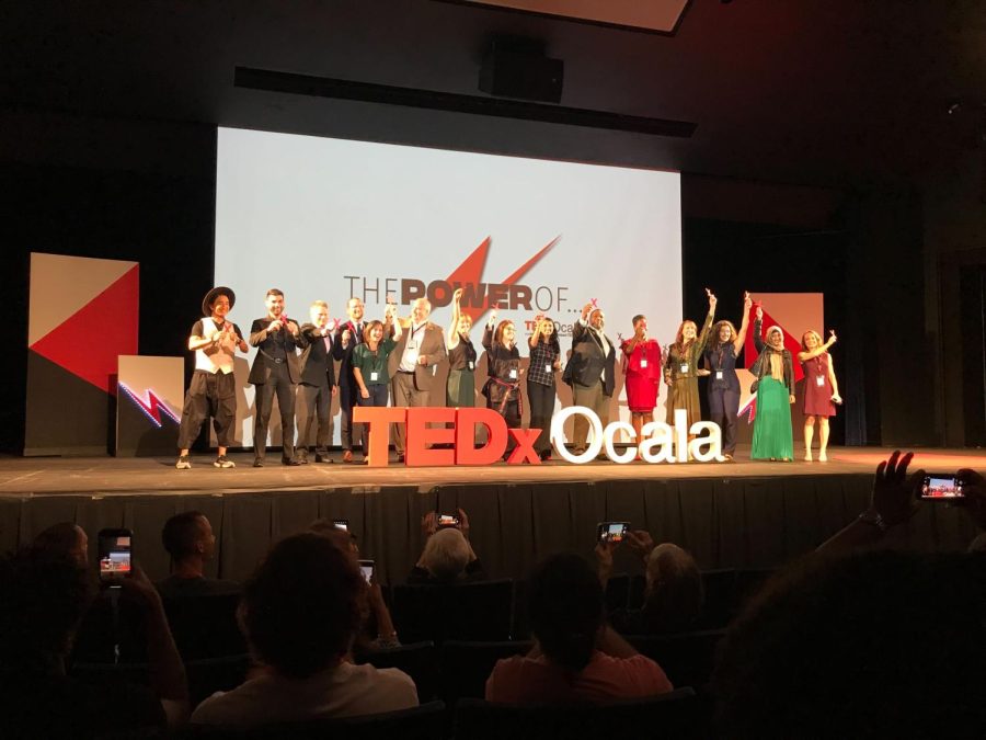 TEDx+Ocala+2022+speakers+pose+together+onstage+at+CFs+Ocala+auditorium.